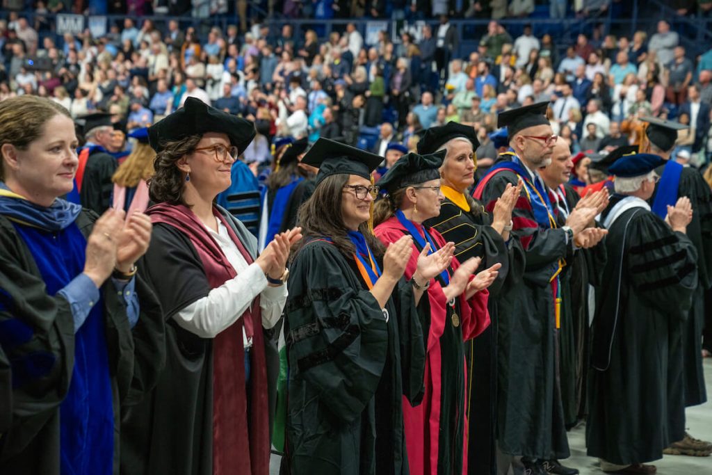 A photo of UMaine faculty members cheering on the graduates