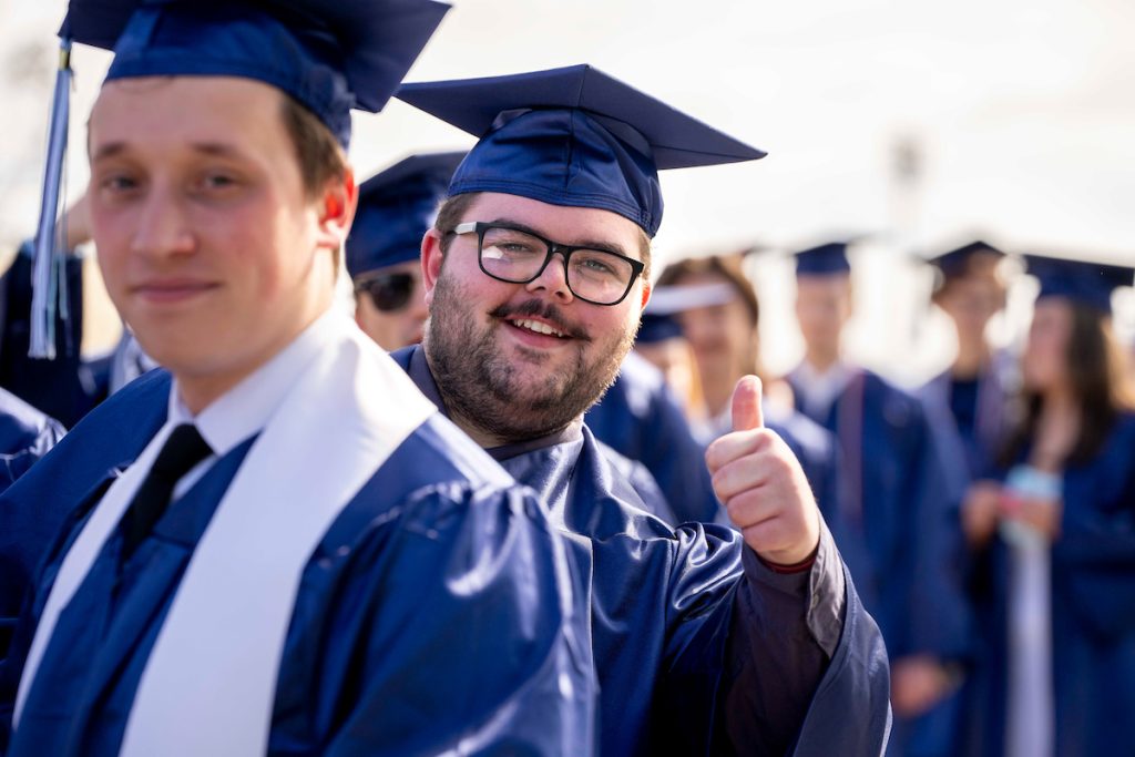 A photo of a graduating student giving a thumbs up