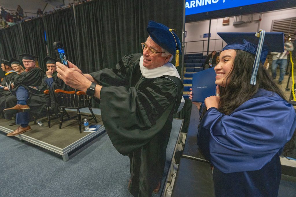 A photo of a professor taking a selfie with a graduate