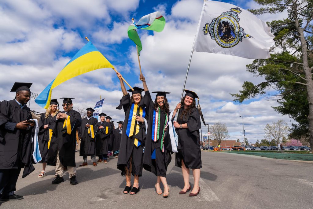 A photo of three graduate students waving flags